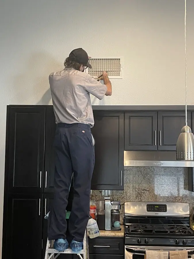 Technician inspecting an air vent during HVAC service in Spring Valley Lake